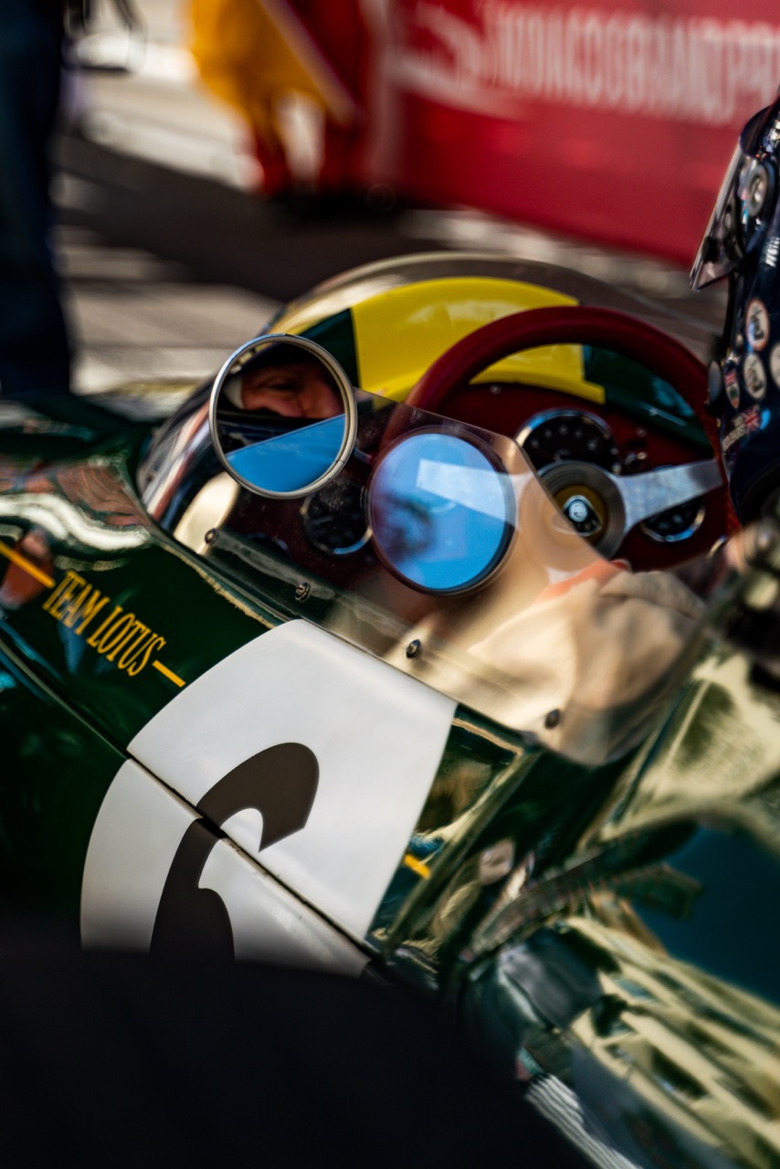 Close-up of a vintage racing helmet with reflective goggles resting on the cockpit of a classic green Formula 1 car. The scene captures the nostalgic details of motorsport, including the car’s polished bodywork and racing number ‘6’