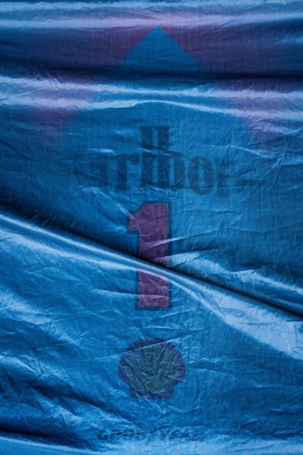 _CLC4446 Close-up of a blue racing cover featuring a faded “number 1” symbol with logos underneath, draped over a structure