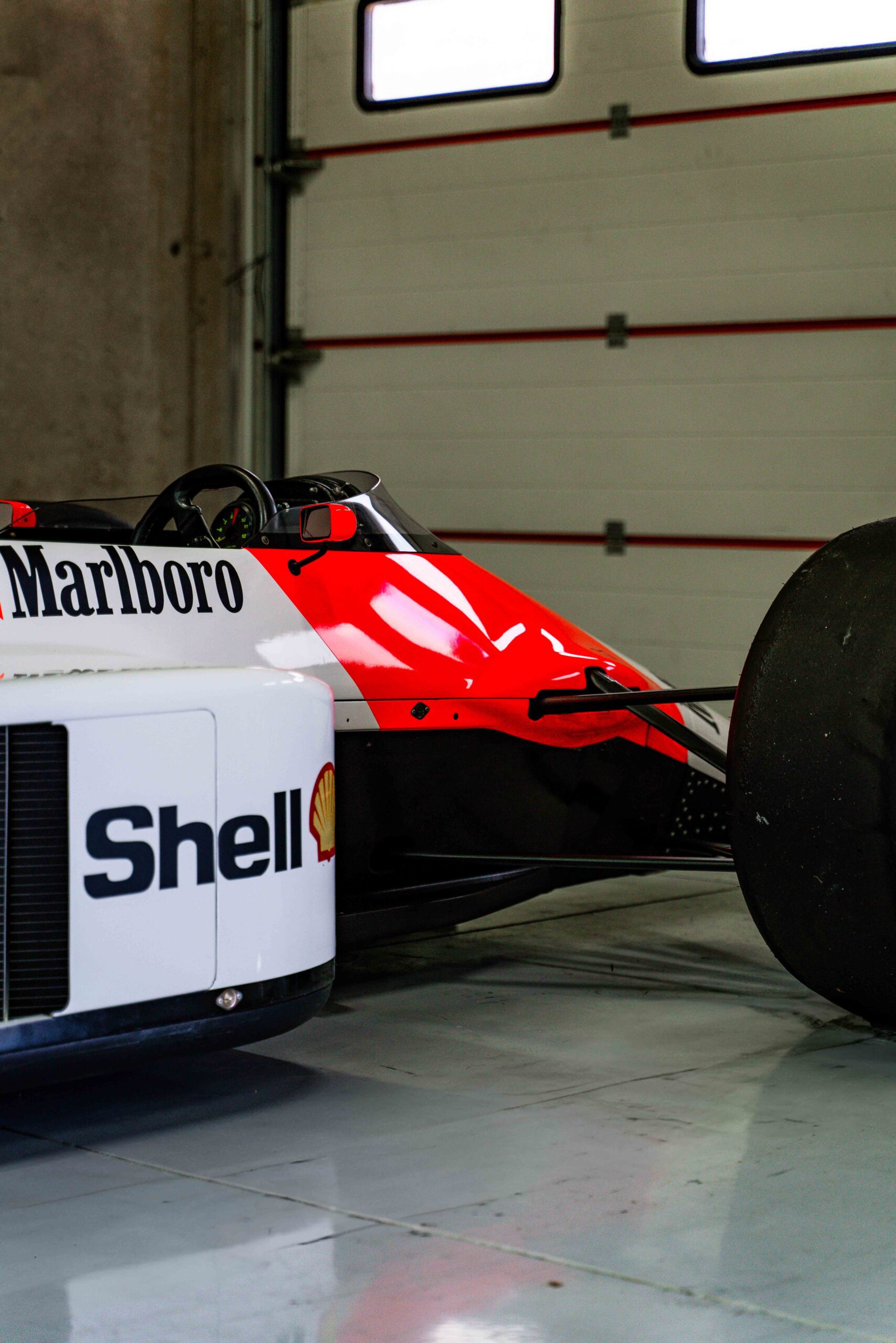 Side view of a classic Formula 1 car with Marlboro and Shell branding parked in a garage