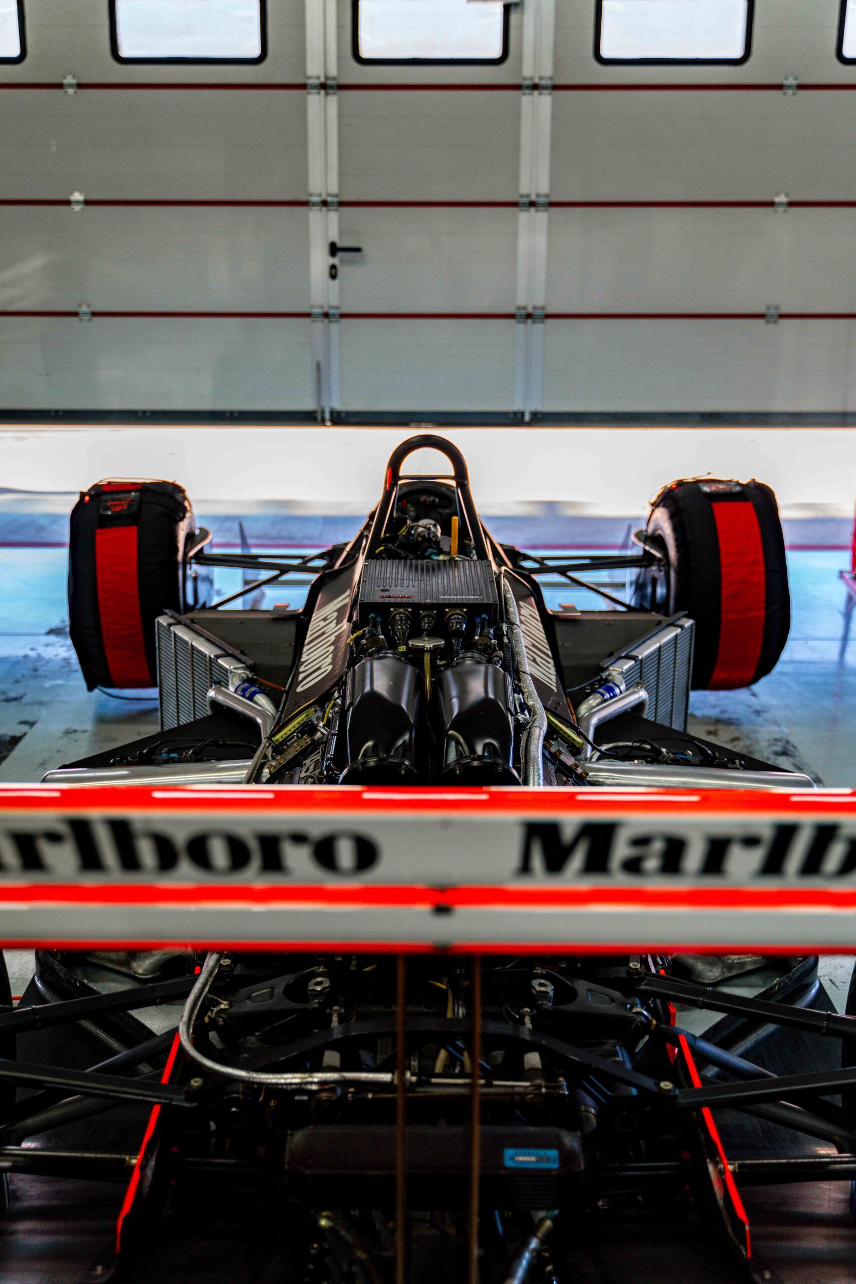 Rear view of a classic Formula 1 car with Marlboro branding under bright garage lights
