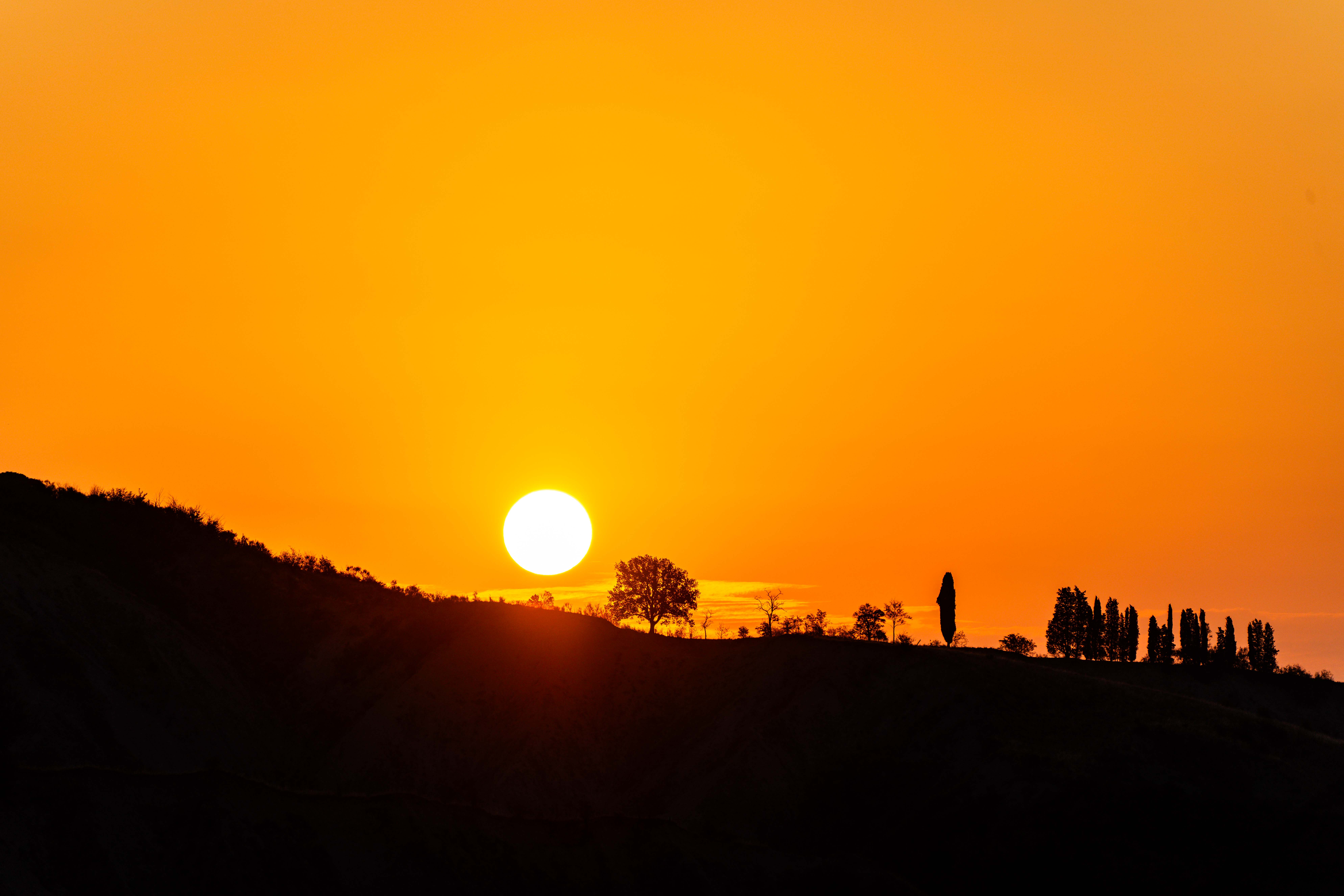 A beautiful sunrise scene with the sun rising over a hilly, wooded landscape