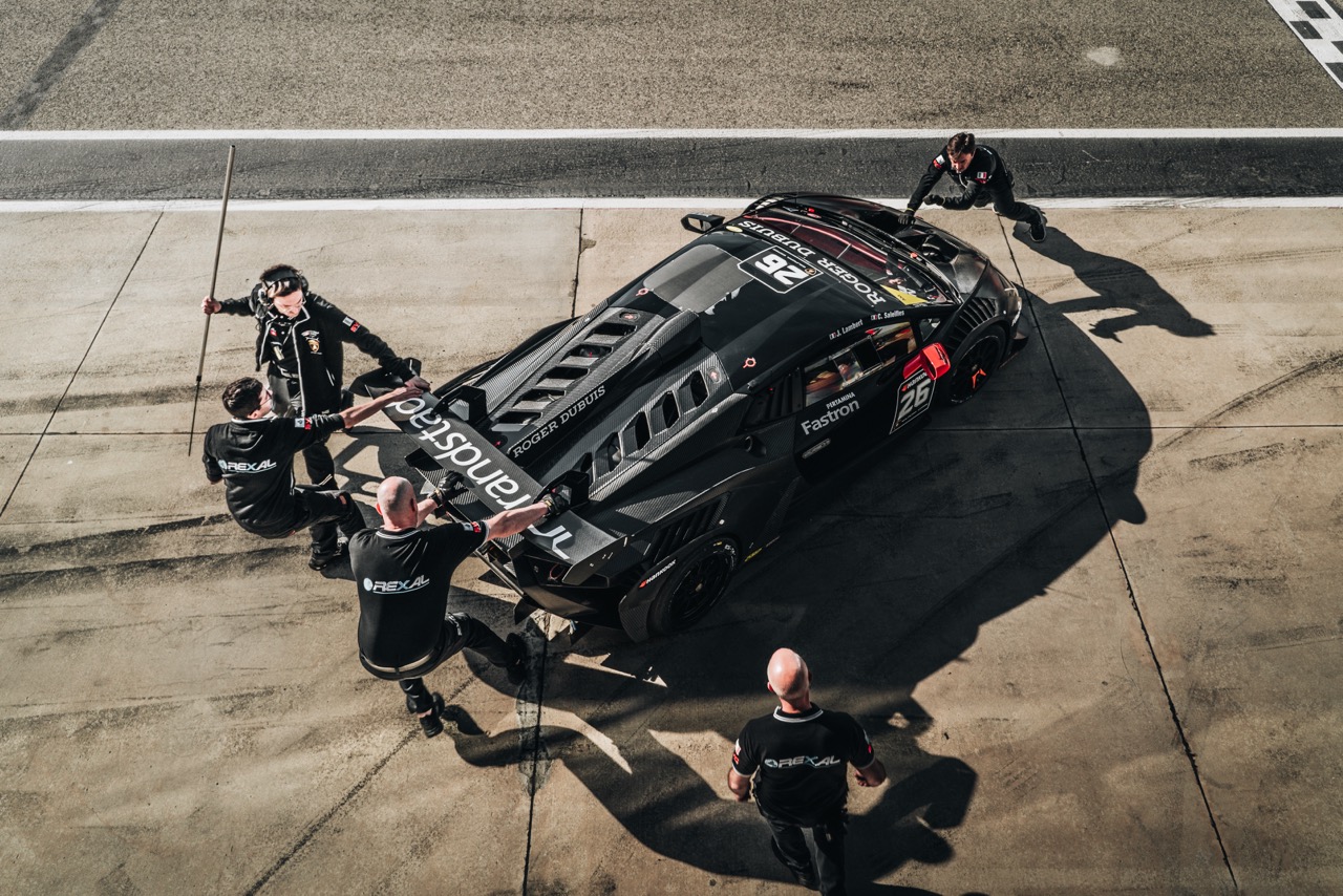 Overhead view of a black Lamborghini race car being prepared by a pit crew on the Imola circuit