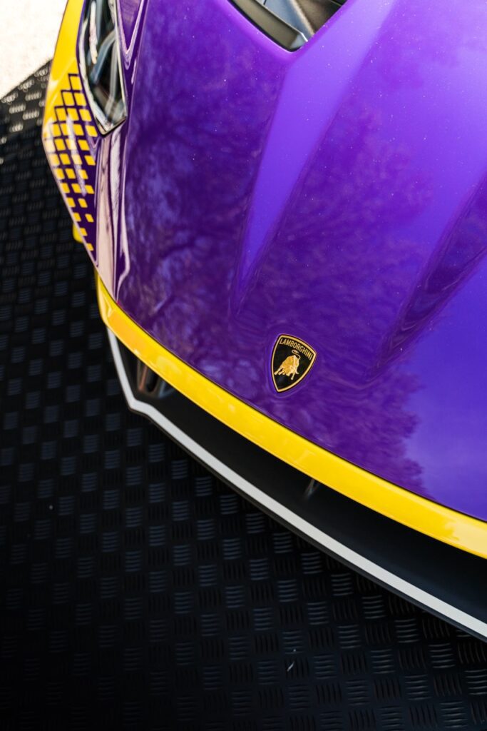 Top view of the front of a Lamborghini in purple and yellow, showcasing the iconic logo and aerodynamic hood design