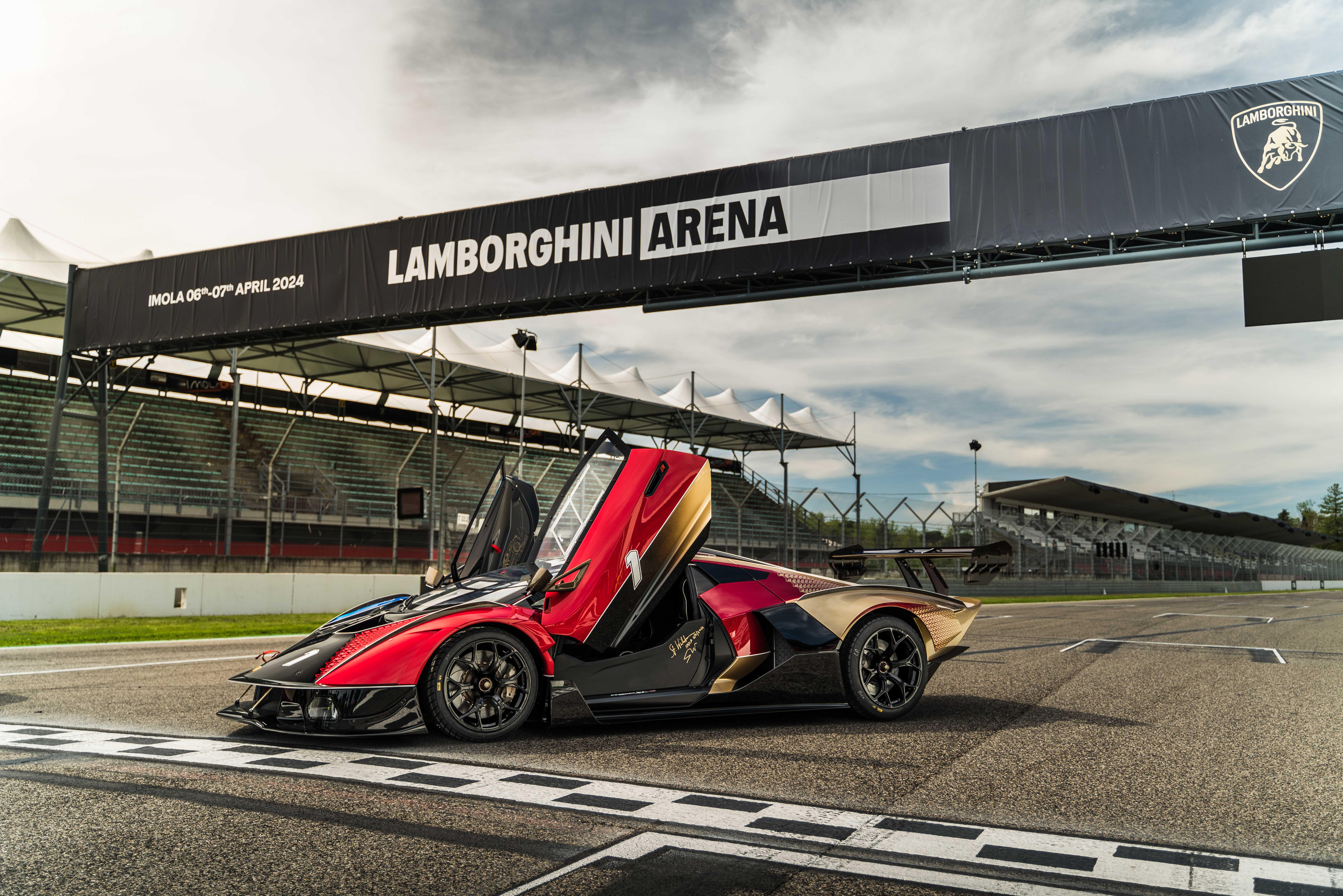 Red Lamborghini with open doors parked at the finish line under the Lamborghini Arena banner at Imola