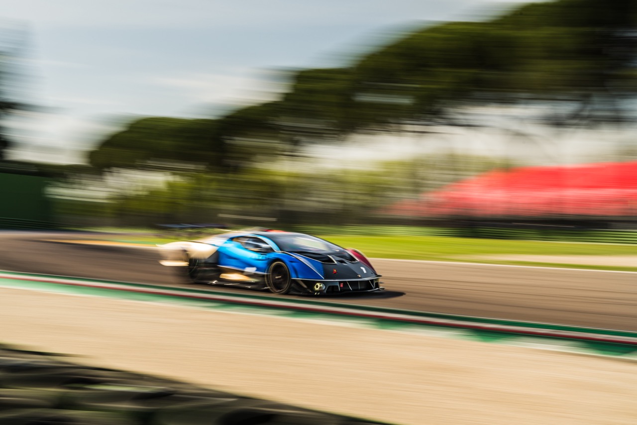 Blurred motion shot of a blue Lamborghini speeding on the Imola racetrack, capturing its dynamic performance