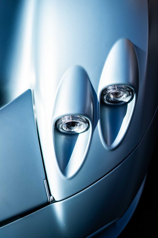 Close-up of dual headlights on a sleek silver sports car, highlighting modern design at The I.C.E. St. Moritz 2023