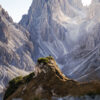 Rugged mountain peaks illuminated by soft sunlight with a rocky foreground.