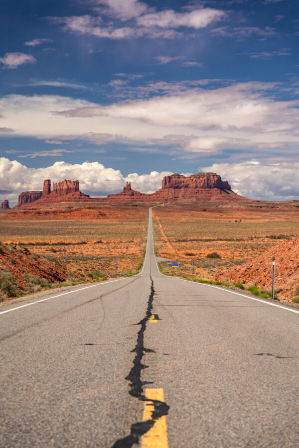 Iconic road leading to Monument Valley's sandstone buttes under dramatic summer clouds, Utah