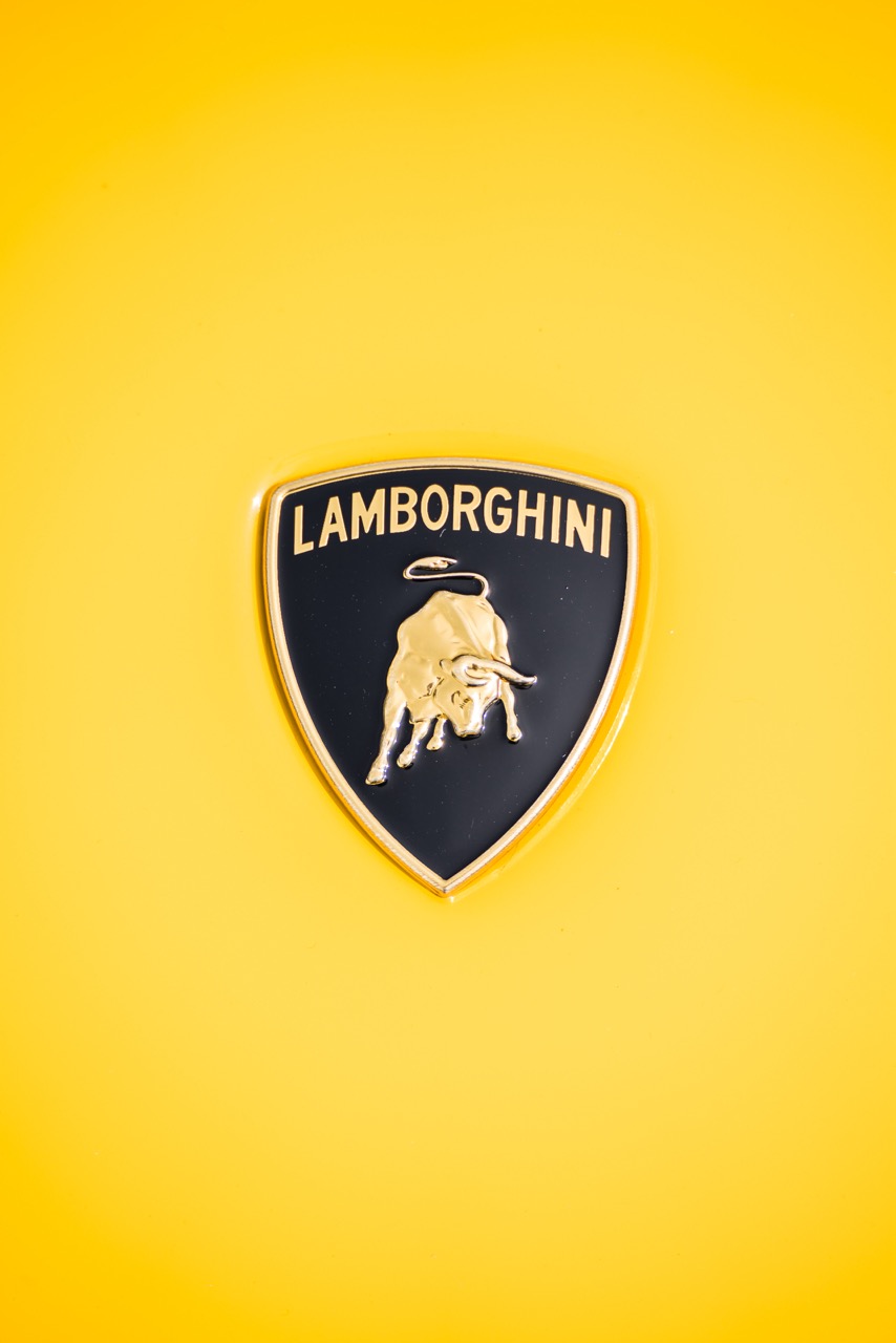 Close-up of the Lamborghini emblem on a vibrant yellow background, emphasizing its iconic branding