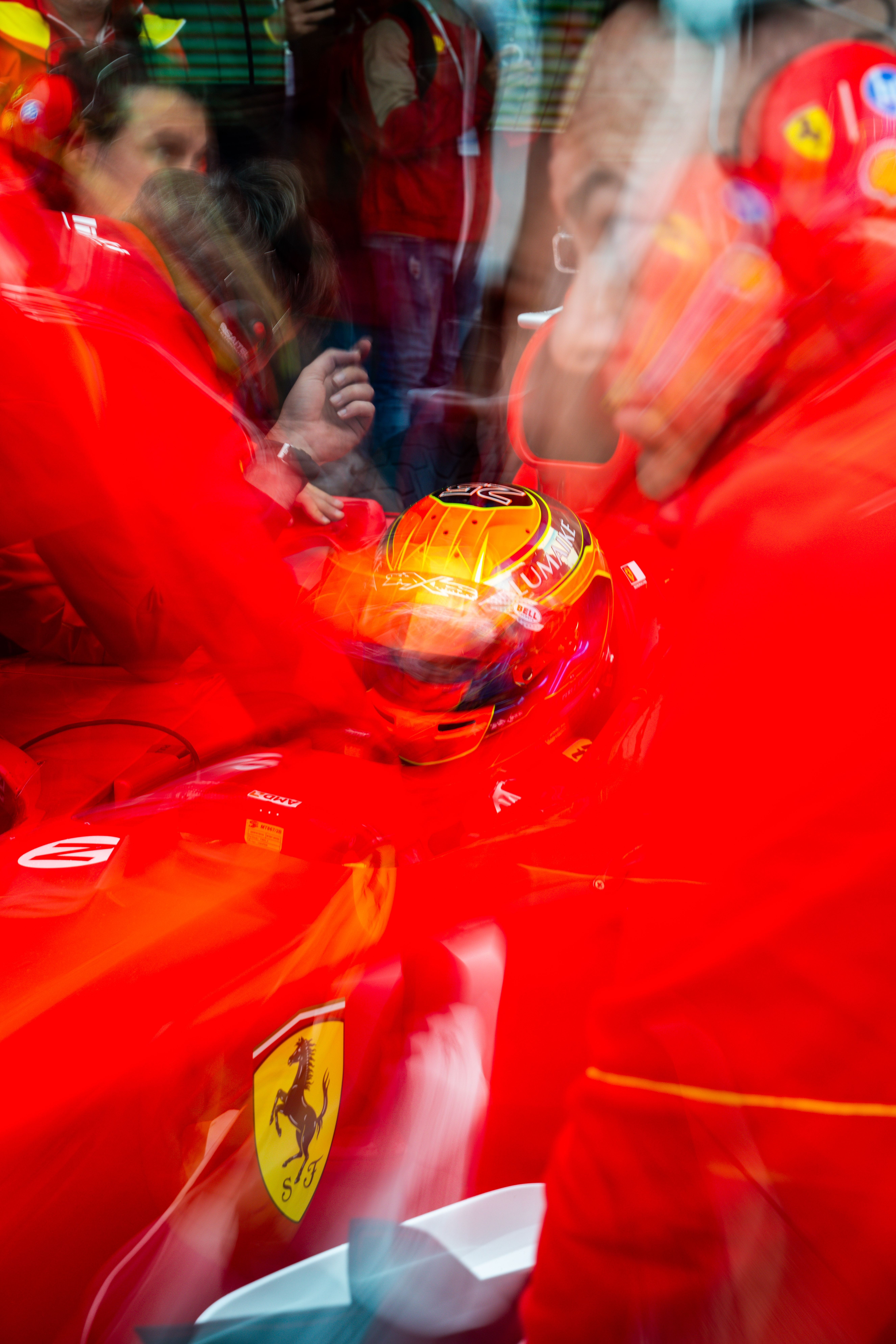 Blurred motion shot of a Ferrari pit crew working with the driver, emphasizing dynamic movement and teamwork