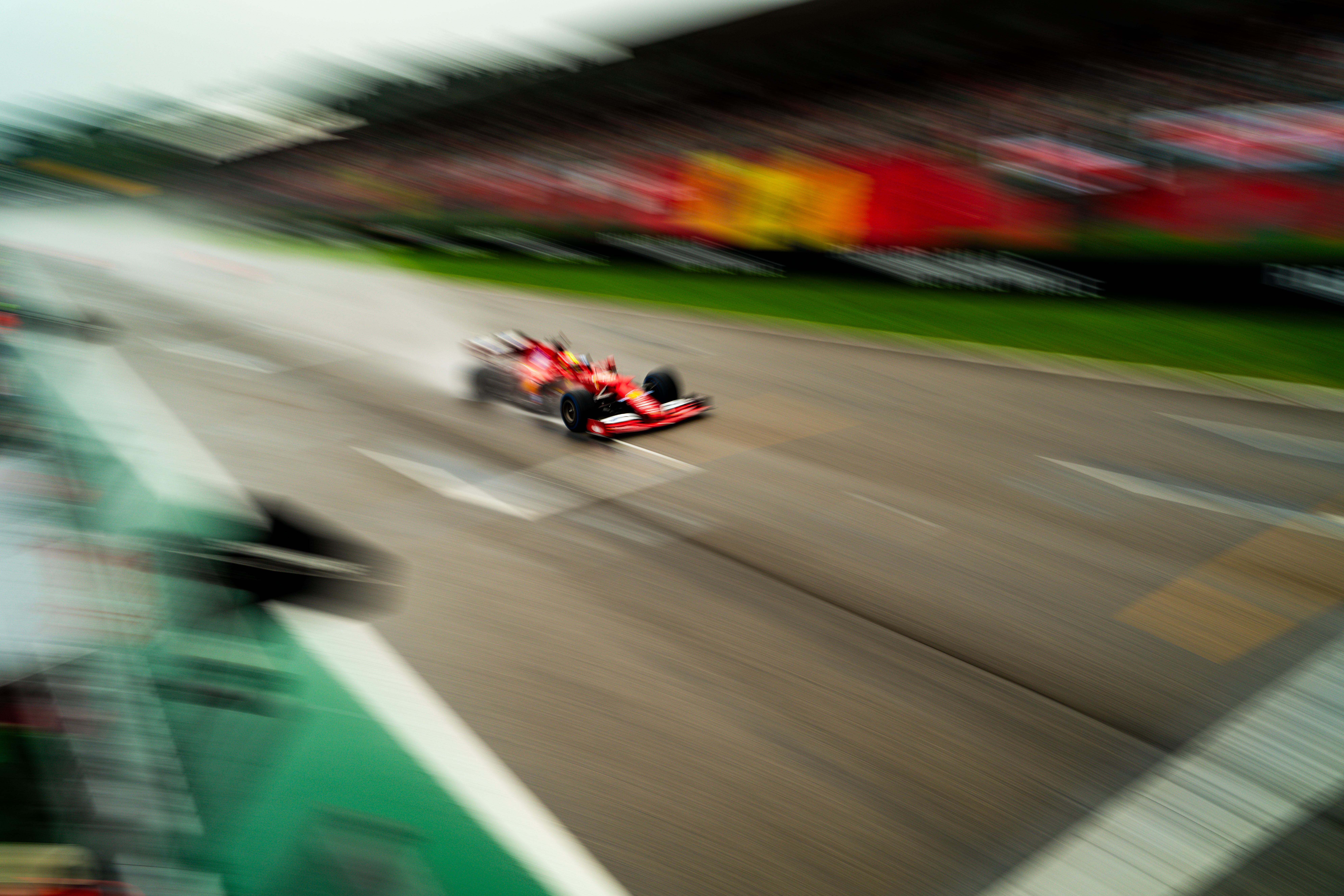 Ferrari Formula 1 car speeding down the track in wet conditions, captured in a motion blur